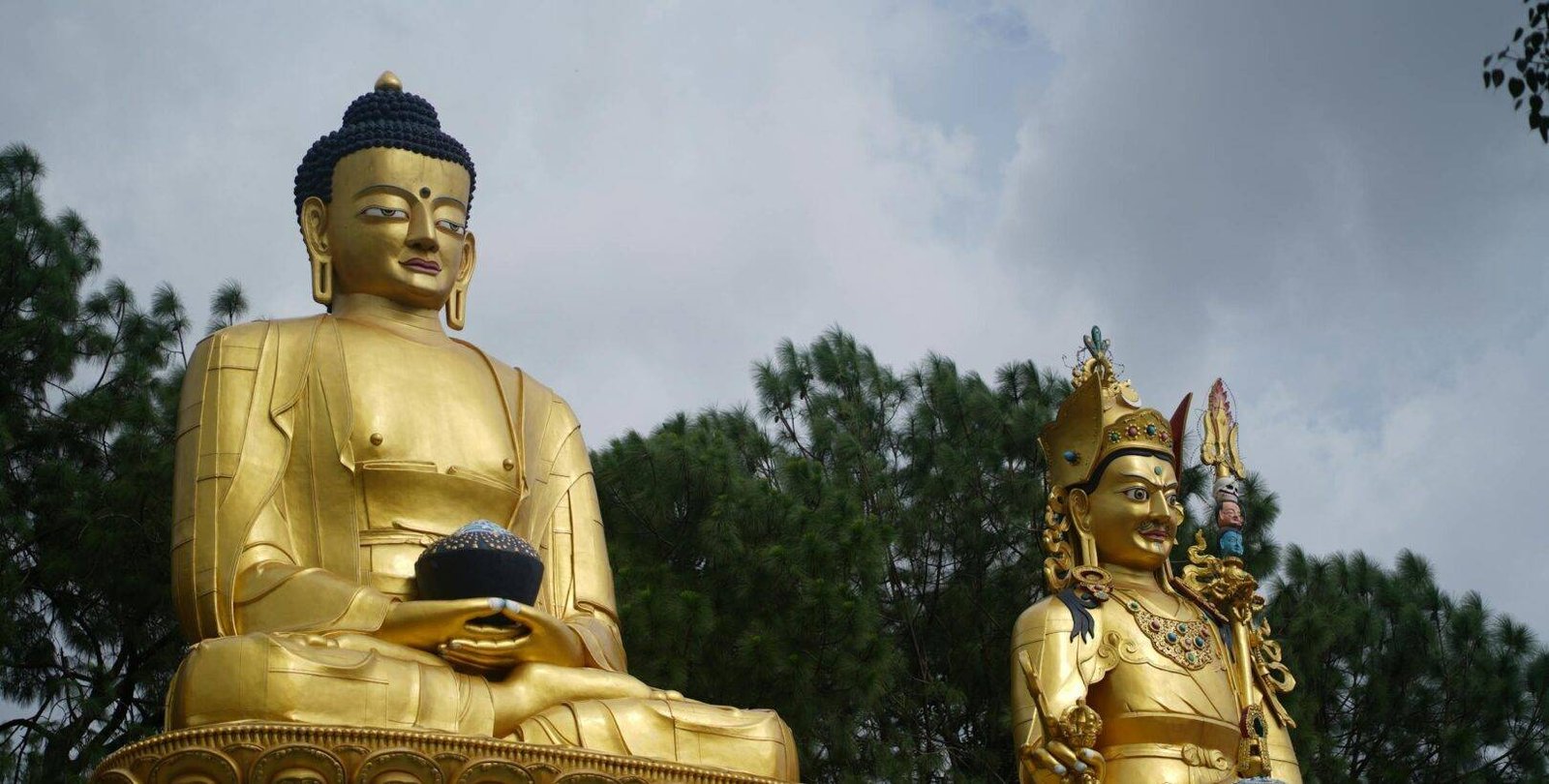 Majestic golden statues at a temple in Kathmandu, Nepal with lush greenery in the background.
